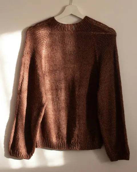A brown knit jumper on a hanger
