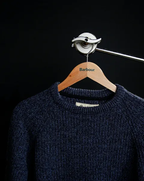A navy wool jumper on a hanger